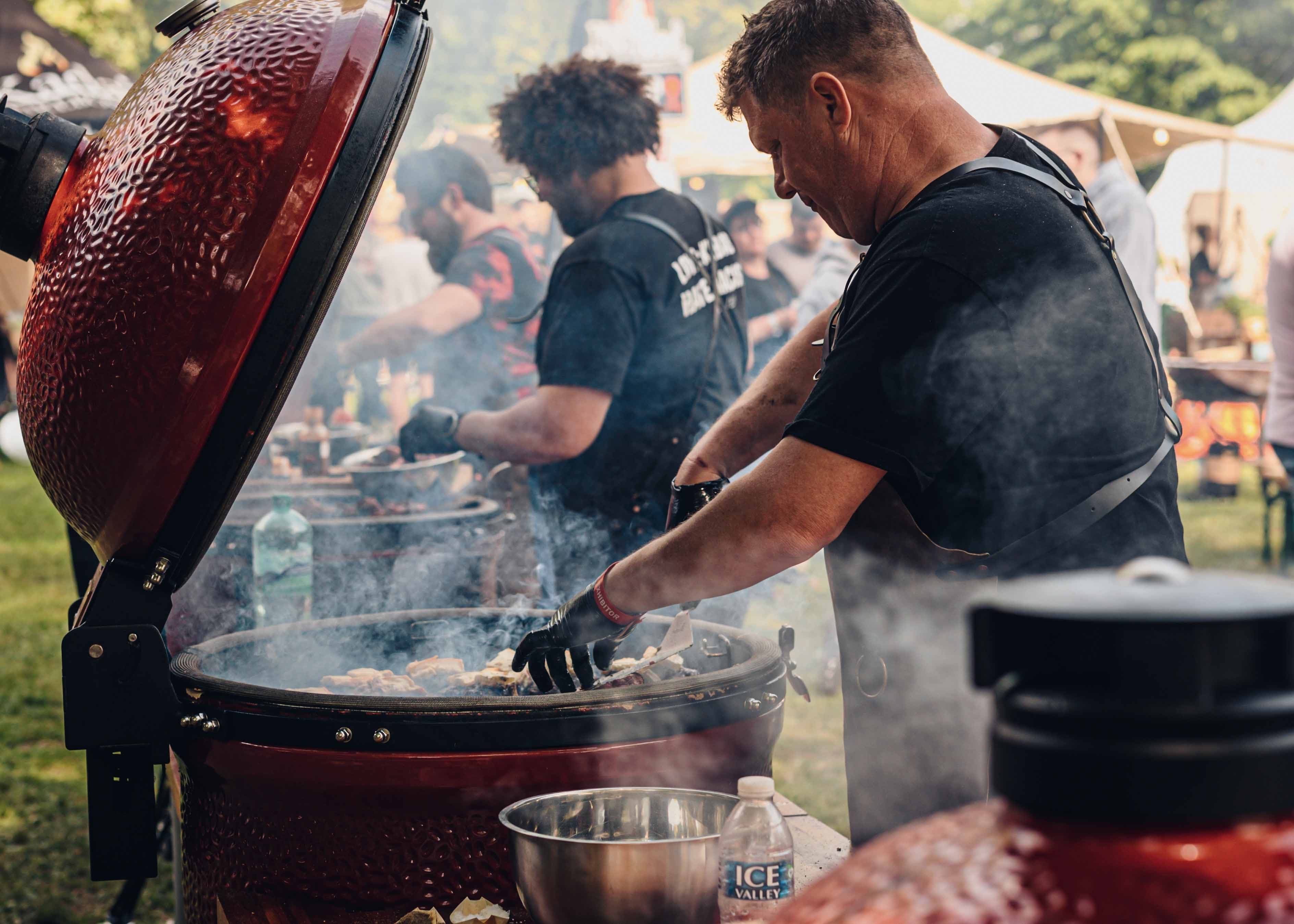 Chef cocinando en Kamado Joe abierto con humo